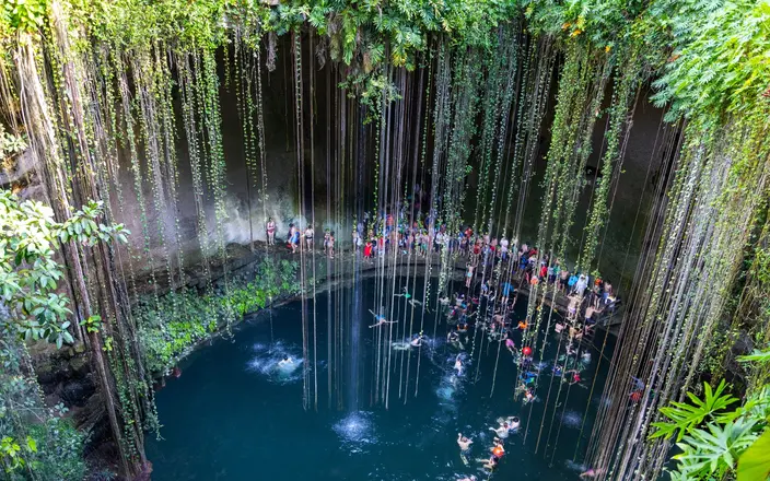 People swimming in a cenote near Tulum, a popular addition to Cancun Mayan ruins excursions.